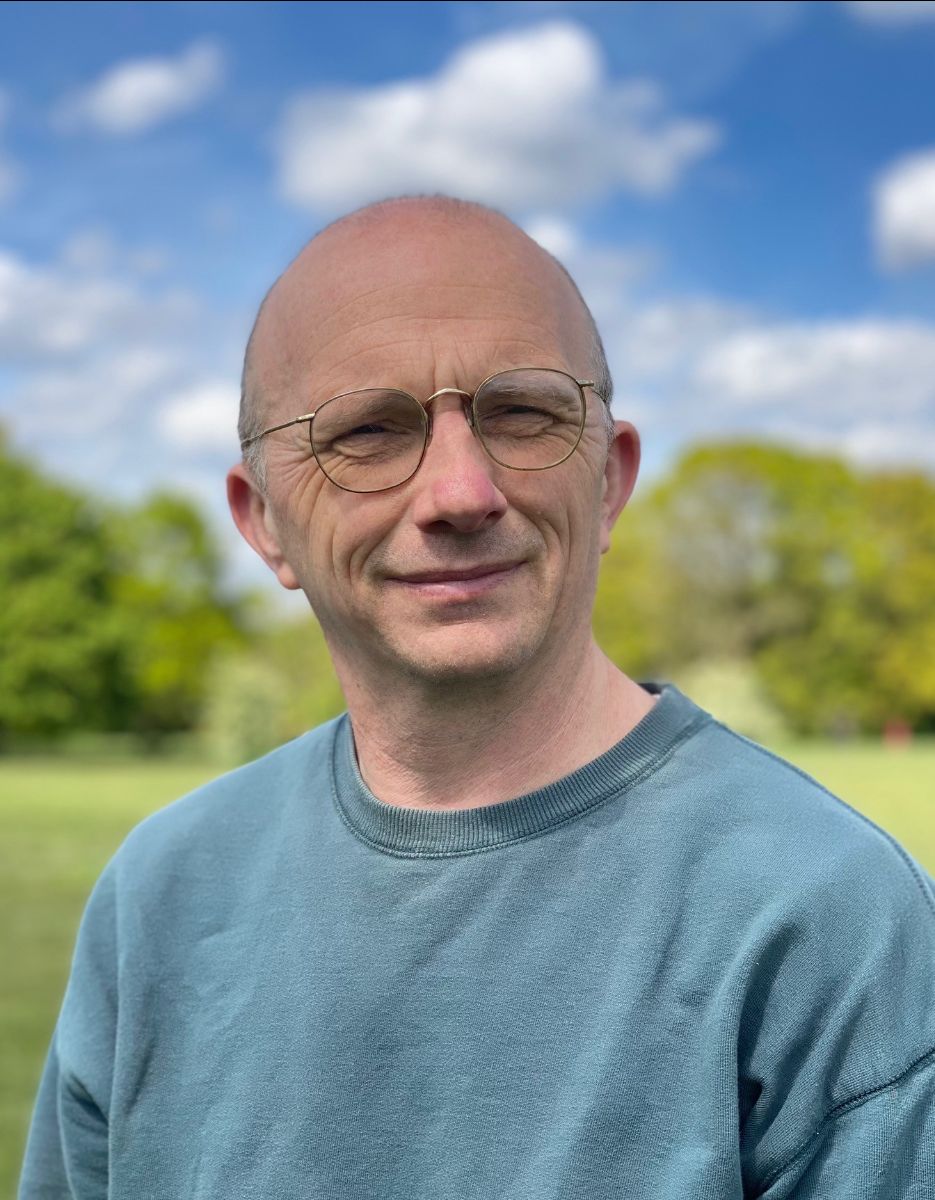 Portrait of Phil Clark smiling in a green field.